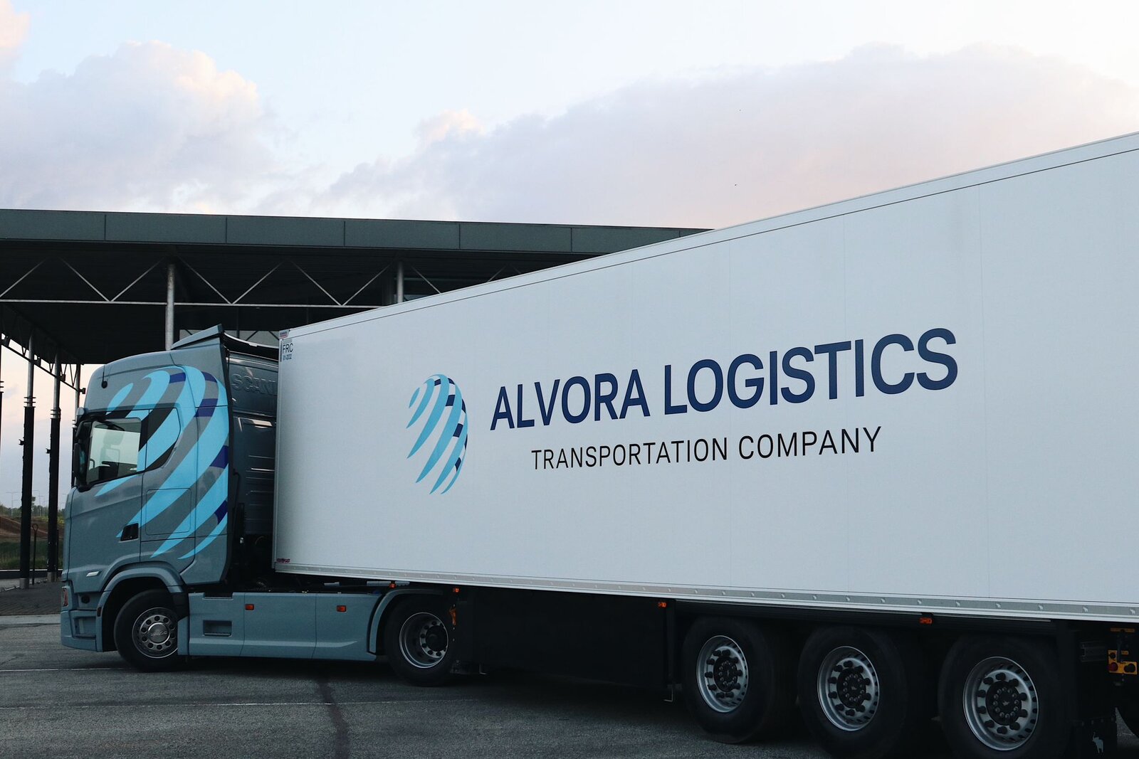 Alvora Logistics grey Scania with white refrigerated trailer at dusk, Alvora Logistics branding clearly visible