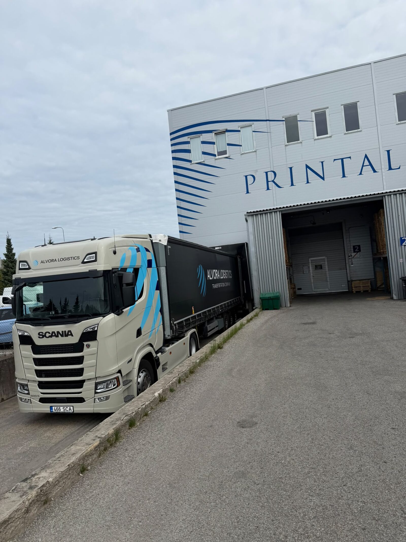 Alvora Logistics white Scania with black curtain-side trailer backed up to a customer loading bay